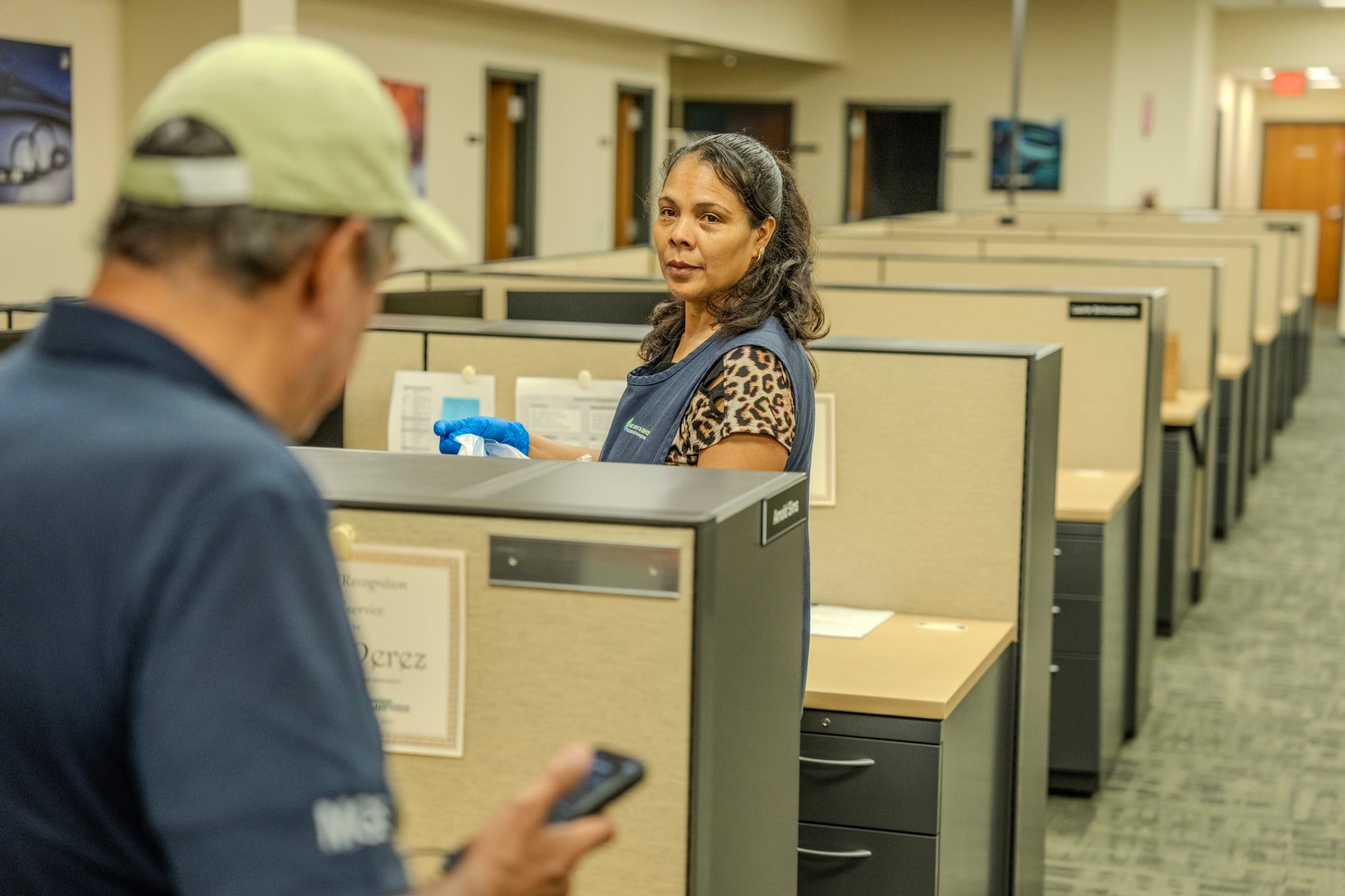 An MGS supervisor holding a phone while walking an office floor with the crew member who services it